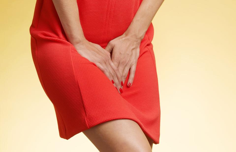 woman in red dress pressing hands on lower abdomen