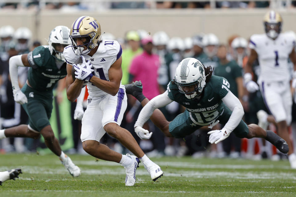 Washington's Jalen McMillan, left, escapes a tackle attempt by Michigan State's Angelo Grose (15) during the first half of an NCAA college football game, Saturday, Sept. 16, 2023, in East Lansing, Mich. (AP Photo/Al Goldis)