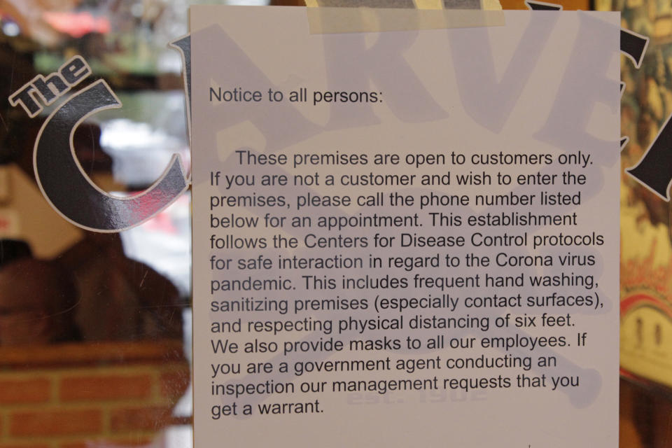 A sign telling state inspectors not to enter without a warrant hangs on the door of the Carver Hangar, a restaurant in Boring, Ore., on Jan. 6, 2021. As coronavirus deaths soar, a growing number of restaurants like Carver Hangar in states across the country are reopening in defiance of strict COVID-19 rules that have shut them down for indoor dining for weeks, or even months. (AP Photo/Gillian Flaccus)