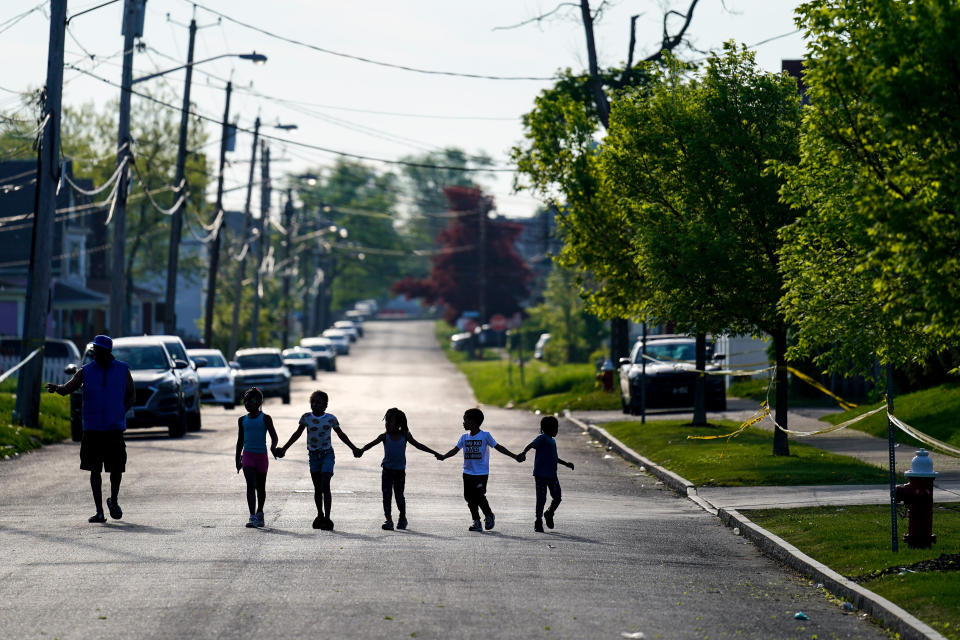 FILE - Children walk hand in hand in a street near the scene of a shooting at a supermarket in Buffalo, N.Y., Sunday, May 15, 2022. Long before an 18-year-old avowed white supremacist inflicted terror at a Buffalo supermarket, the city's Black neighborhoods, like many others around the nation, had been dealing with wounds that are generations old. (AP Photo/Matt Rourke, File)