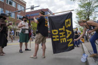 Abby McGinty straightens out Jojo Vinay's flag protesting the designated hitter rule shortly before the Pittsburgh Pirates take on the Chicago Cubs in the Pirates home opening baseball game at PNC Park in Pittsburgh, Thursday, April 8, 2021. (Steven Mellon/Pittsburgh Post-Gazette via AP)