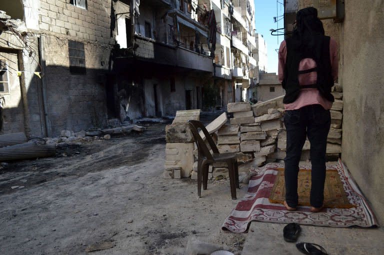 An opposition fighter prays in a street in Syria's northern city of Aleppo on September 11, 2013