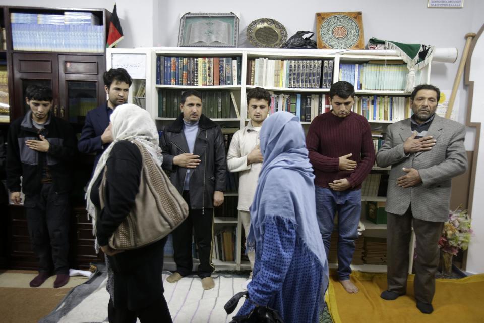 Afghan women who live in Greece, file past the survivors of a boat sinking, to pay their respect at a makeshift basement mosque in western Athens Friday, Jan. 24, 2014. Twelve people, mostly children, are believed to have perished in Monday's sinking. Only two bodies have been found. Greece's merchant marine minister said Friday the survivors of a fatal migrant boat sinking changed their accounts of the incident, initially saying the Greek Coast Guard saved them but later accusing it of badly mishandling the rescue operation. (AP Photo/Thanassis Stavrakis)