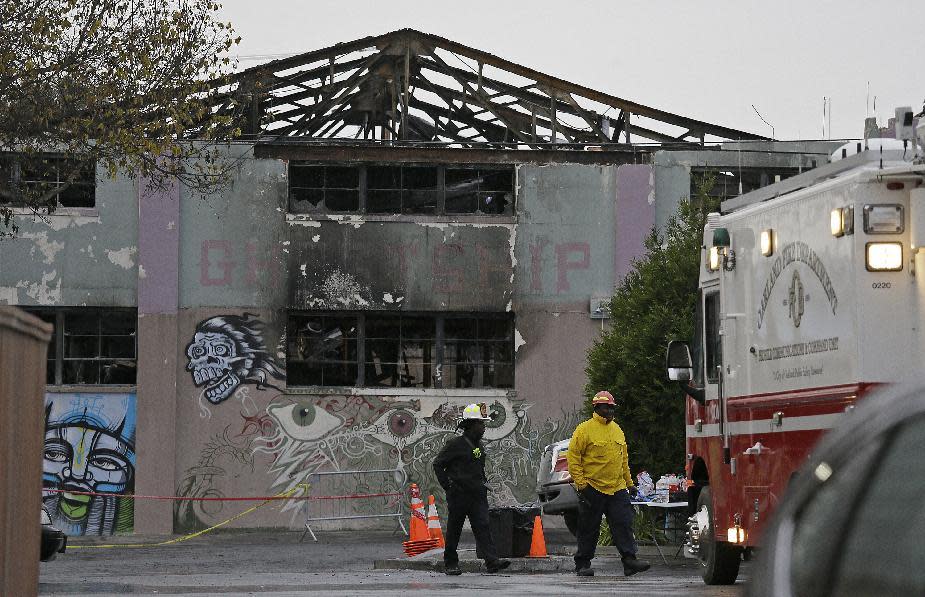 FILE - In this Dec. 7, 2016 file photo, Oakland fire officials walk past the remains of the Ghost Ship warehouse damaged from a deadly fire in Oakland, Calif. California lawmakers will hold a hearing to discuss the Oakland warehouse fire that killed 36 partygoers and how to prevent future tragedies at unpermitted live-work spaces popping up in pricey California cities. (AP Photo/Eric Risberg, File)