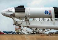 Crews work on the SpaceX Crew Dragon, attached to a Falcon 9 booster rocket, as it sits horizontal on Pad39A