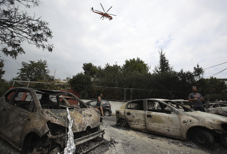 <p>A firefighting helicopter flies above burned-out cars in Mati east of Athens, Tuesday, July 24, 2018. (Photo: Thanassis Stavrakis/AP) </p>