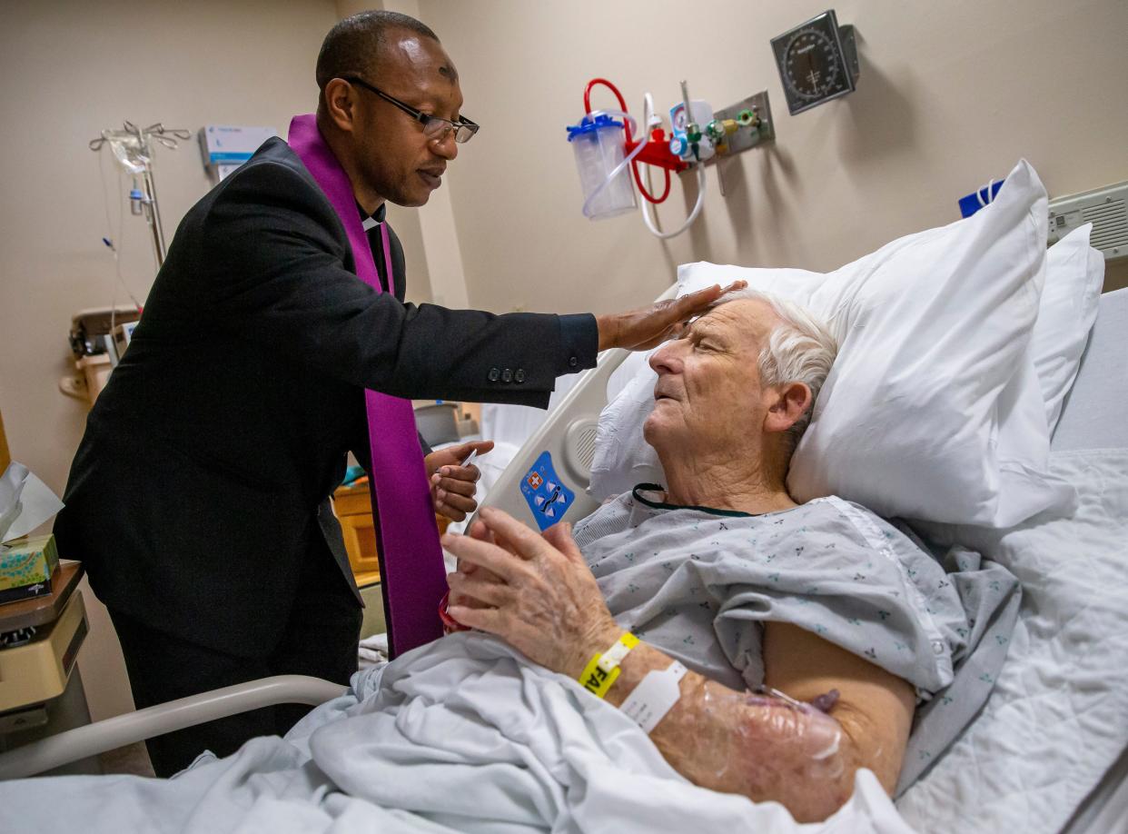 Rev. Fredrick "Freddie" Mbiere prays with HSHS St. John's Hospital patient James Degenhart after distributing ashes for Ash Wednesday at his bedside in HSHS St. John's Hospital, Wednesday, Feb. 26, 2020, in Springfield, Ill.  Rev. Mbiere, the chaplain of HSHS St. John's Hospital, visited with over 50 patients delivering ashes for Ash Wednesday, officially known as the Day of Ashes, which marks the start of the Lenten period leading up to Easter. [Justin L. Fowler/The State Journal-Register] 
