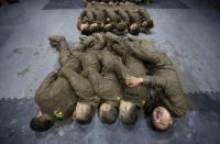 Students hold each other for warmth as they sleep during a break in between high intensity training at Tianjiao Special Guard/Security Consultant camp on the outskirts of Beijing December 1, 2013. Former Chinese soldier Chen Yongqing has big ambitions for his bodyguard training school Tianjiao, which he says is China's first professional academy to train former soldiers and others as personal security guards. Chen charges 500,000 yuan ($82,400) a year for each protector as China's rich and famous look to bolster their safety and sense of importance. Picture taken December 1, 2013. REUTERS/Jason Lee (CHINA - Tags: BUSINESS SOCIETY TPX IMAGES OF THE DAY) ATTENTION EDITORS: PICTURE 20 26 FOR PACKAGE 'CHINA'S BODYGUARD SCHOOL' TO FIND ALL SEARCH 'TIANJIAO'