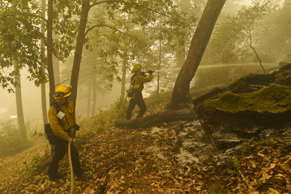 Firefighters, part of joint task force of South Pasadena and San Gabriel fire departments, hose down hot spots as smoke from the CZU August Lightning Complex Fire fills the air Saturday, Aug. 22, 2020, in Boulder Creek, Calif. (AP Photo/Marcio Jose Sanchez)