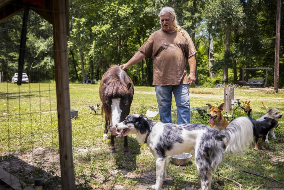 Edward Gibson checks on his various pets outside of his home at the entrance of Sam Houston Lakes Estates on June 28, 2023.