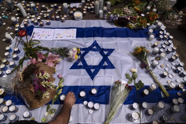 FILE - People light candles at the site of Thursday night's shooting attack that killed two and wounded over 10, in Tel Aviv, Israel, Friday, April 8, 2022. In the weeks before a rare confluence of major Jewish, Christian and Muslim holidays, with tens of thousands of visitors expected in Jerusalem for the first time since the pandemic, Israeli, Palestinian and Arab leaders discussed how to calm tensions. It hasn't worked out as planned. (AP Photo/Oded Balilty, File)