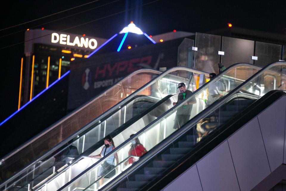 A few people in masks ride down an escalator on the Las Vegas Strip