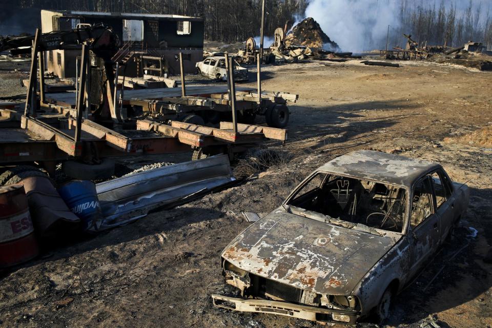 Scorched trees, vehicles and debris cover the landscape of a sawmill consumed by wildfires in the community Santa Olga, Chile, Tuesday, Jan. 31, 2017. The fires have been raging in central and southern Chile, fanned by strong winds, hot temperatures and a prolonged drought. (AP Photo/Esteban Felix)