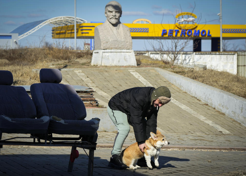 A local resident plays with a dog in front of a statue of former Soviet leader Vladmir Lenin, in Comrat, Moldova, Saturday, March 12, 2022. Across the border from war-engulfed Ukraine, tiny, impoverished Moldova, an ex-Soviet republic now looking eagerly Westward, has watched with trepidation as the Russian invasion unfolds. In Gagauzia, a small, autonomous part of the country that's traditionally felt closer to the Kremlin than the West, people would normally back Russia, which they never wanted to leave when Moldova gained independence. (AP Photo/Sergei Grits)
