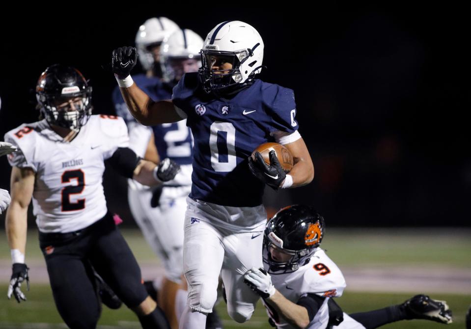 East Lansing's Jace Clarizio, center, runs against Byron Center's Luke Laska, left, and Andrew Kroft (9), Friday, Nov. 10, 2023, in East Lansing, Mich. East Lansing won 42-20.