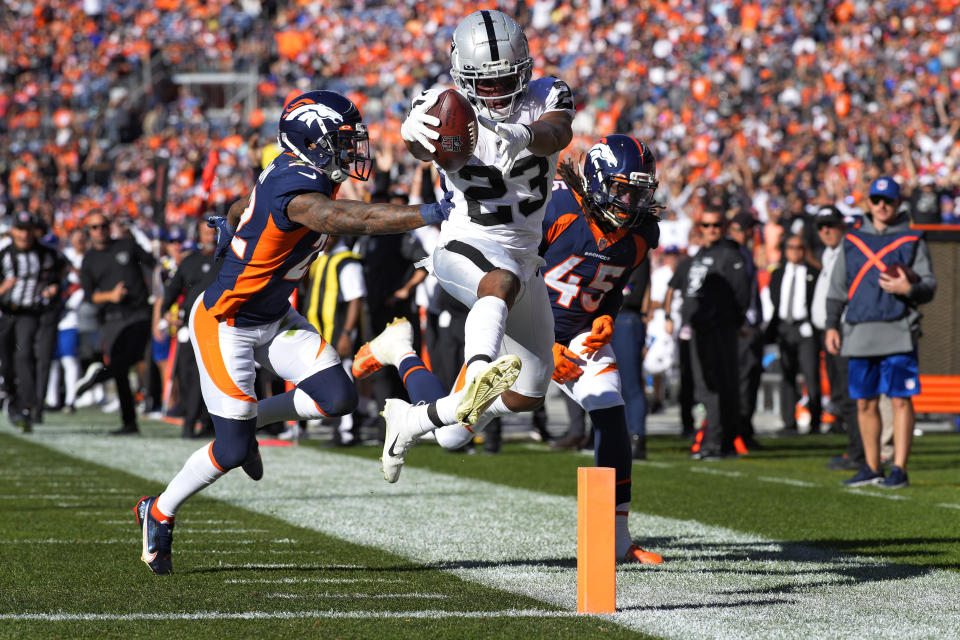 Las Vegas Raiders running back Kenyan Drake scores a touchdown as Denver Broncos cornerback Kyle Fuller (23) and inside linebacker A.J. Johnson (45) defend during the first half of an NFL football game, Sunday, Oct. 17, 2021, in Denver. (AP Photo/David Zalubowski)