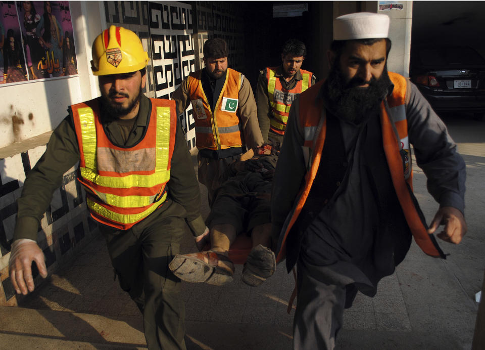 In this Tuesday, Feb. 11, 2014 photo, Pakistani rescue workers remove a body from the site of a grenade attack inside a movie theater in Peshawar, Pakistan. The Pakistani government has recently opened negotiations with domestic militants called the Pakistani Taliban designed to end years of fighting in the northwest that has cost thousands of lives and forced hundreds of thousands of people to flee their homes. (AP Photo/Mohammad Sajjad)