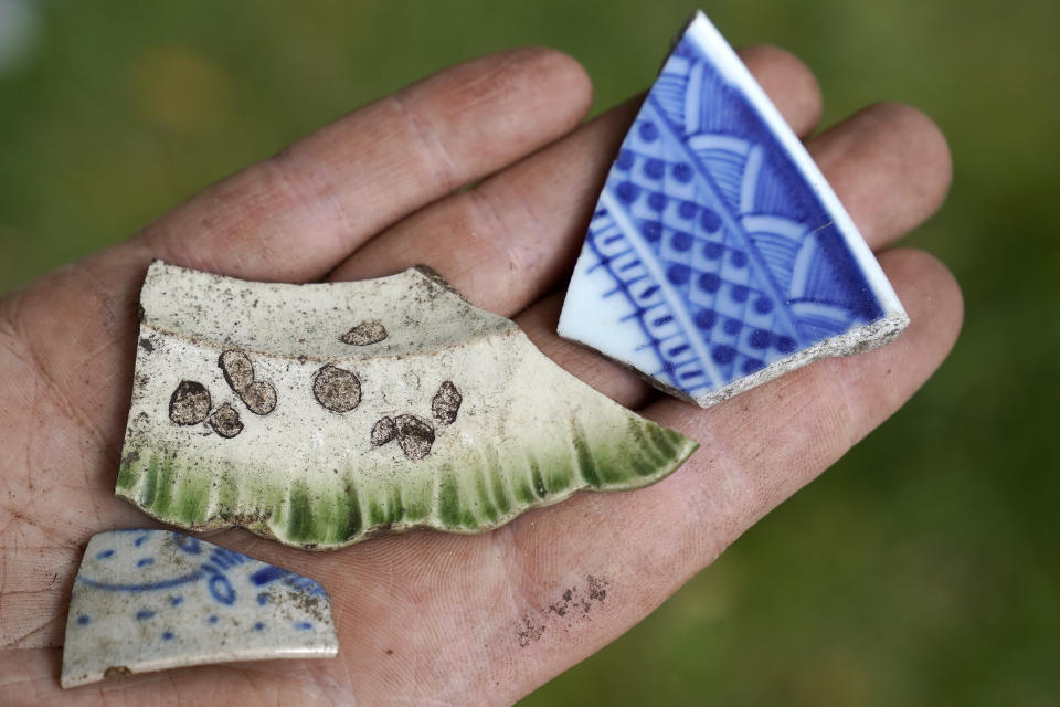 University of Massachusetts Boston research scientist Christa Beranek, of Arlington, Mass., holds ceramic fragments estimated to be from the late 18th and early 19th centuries found at an excavation site, Wednesday, June 9, 2021, on Cole's Hill, in Plymouth, Mass. Beranek is part of a team of archaeologists excavating the grassy hilltop that overlooks iconic Plymouth Rock one last time before a historical park is built on the site. (AP Photo/Steven Senne)