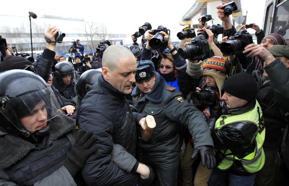 In this Sunday, March 18, 2012 photo, police officers detain Sergei Udaltsov outside the Kremlin-loyal NTV television station, in Moscow. Russian opposition and human rights groups on Monday, Nov. 19, 2012, urged Western consumer products giants to stop "financing politically motivated persecution" by advertising on a Kremlin-friendly TV network known for its biased coverage of government critics and demonstrations against President Vladimir Putin. In the wake of unprecedented anti-Putin protests that followed last December's rigged parliament vote and Putin's return to the Kremlin in May, NTV has run dozens of news reports, talk shows and pseudo-documentaries accusing opposition leaders of plotting coups and terrorist attacks, of receiving money from Western governments, and of hiring migrant workers and neo-Nazis to participate in anti-Putin rallies. (AP Photo/Sergey Ponomarev)