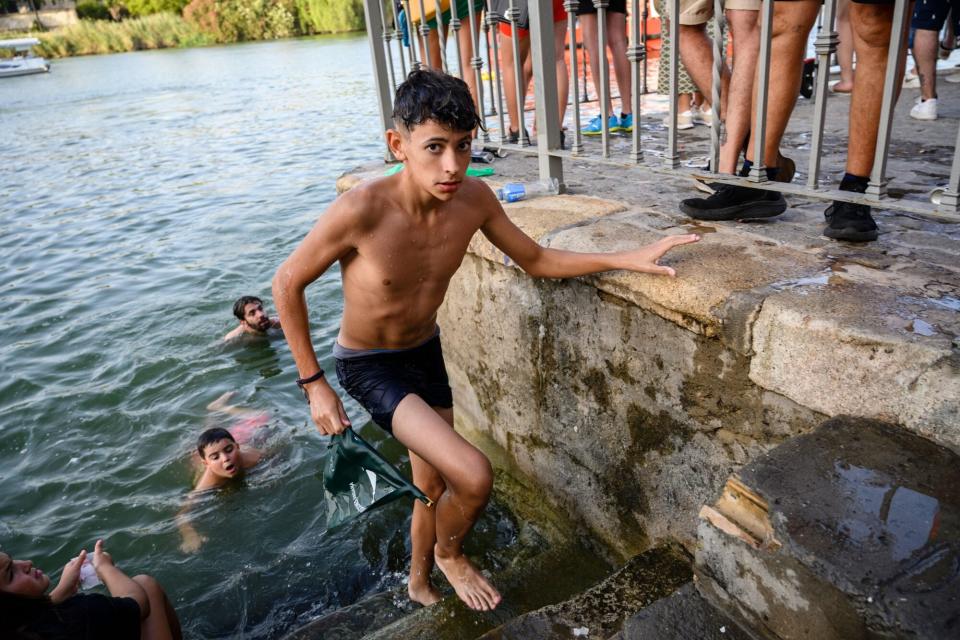 July 23, 2022, Seville, Andalusia, Spain: A man reachs the Guadalquibir river bank after one he got the flag, winning the greasy pole game during the ''Vela de Santiago y Santa Ana''. A tradition that tooks place in the neighborhood of Triana the last week of July. (Credit Image: © Angel Garcia/ZUMA Press Wire)