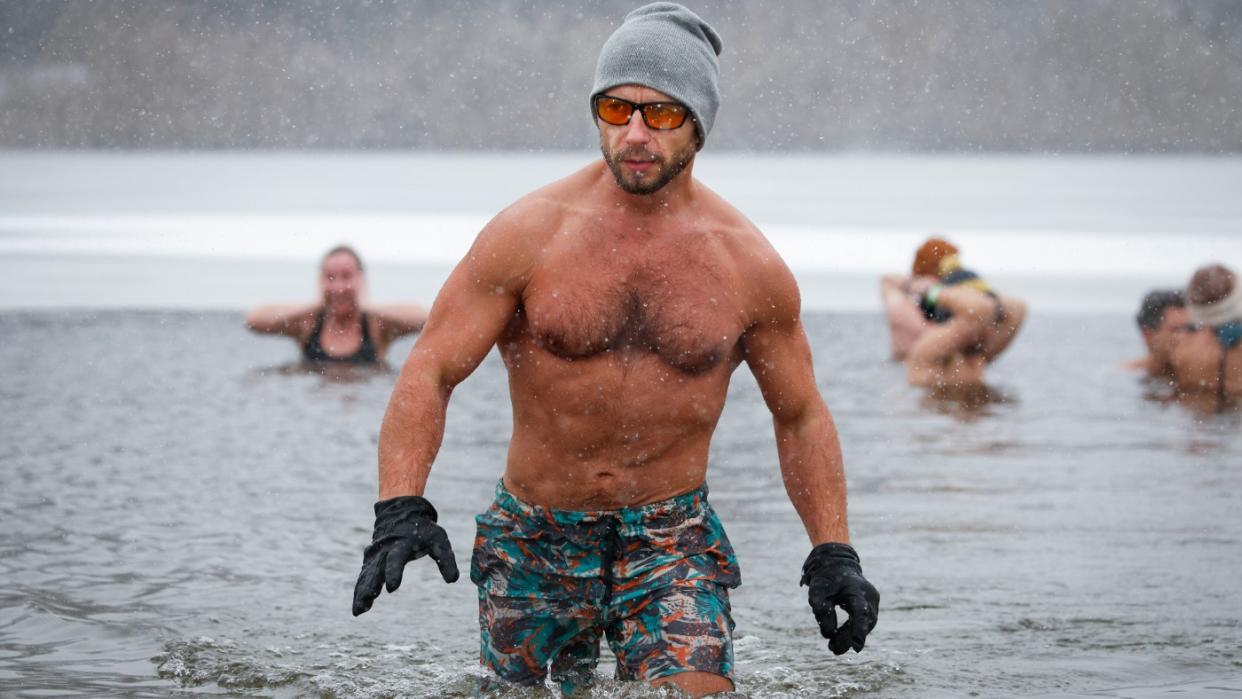  A man emerges from a swim in a lake. 