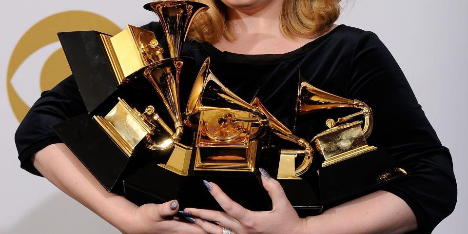 adele holding grammys trophy stack