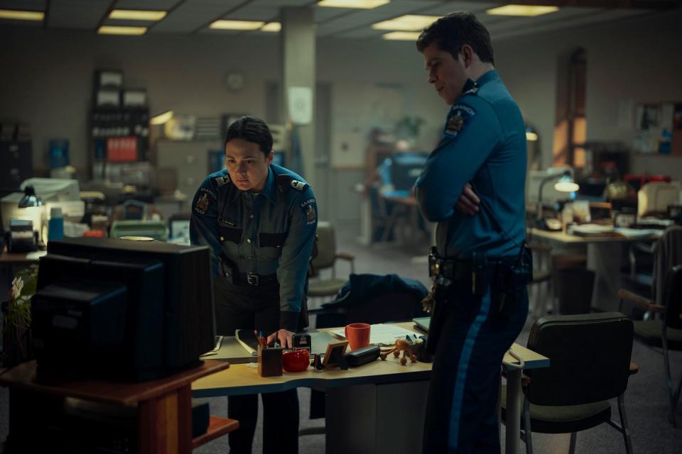 a couple of men standing in a room with a computer and a desk