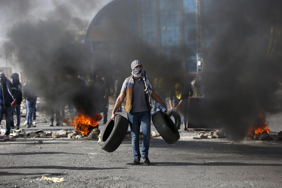 Palestinian demonstrators burn tires as they clash with Israeli troops during the protest against the U.S. announcement that it no longer believes Israeli settlements violate international law., at checkpoint Beit El near the West Bank city of Ramallah, Tuesday, Nov. 26, 2019, (AP Photo/Majdi Mohammed)