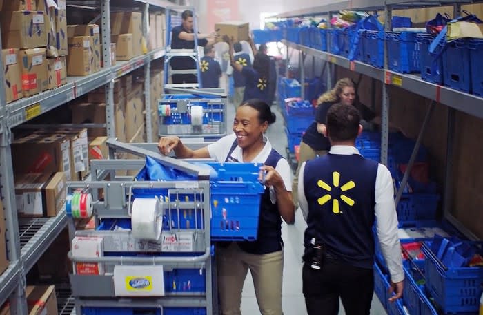 Walmart employees filling baskets from shelves at one of its fulfillment centers.