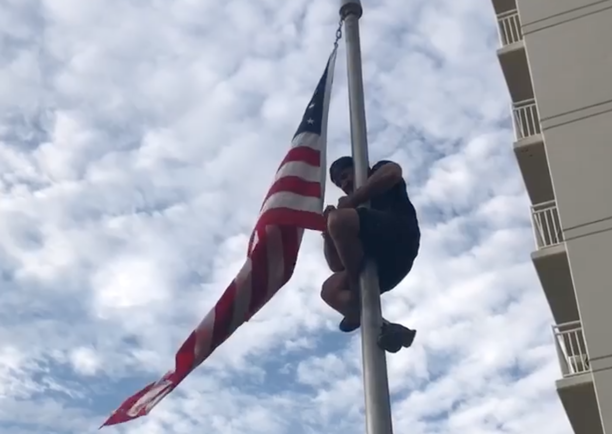 Dom Raso, a Navy SEAL, climbs a flagpole at a Navy SEAL monument in Virginia Beach in order to fix a wayward flag. (Photo: Facebook)