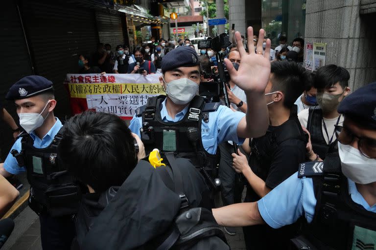 Manifestantes a favor de la democracia son rodeados por agentes de policía mientras llevan una pancarta contra la elección del jefe del ejecutivo cerca de un colegio electoral en Hong Kong, el domingo 8 de mayo de 2022.