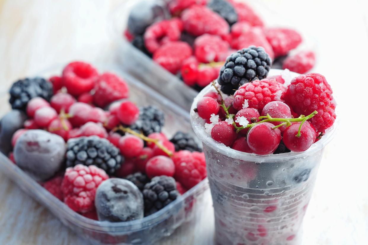 selection of frozen berries in plastic containers on wooden table