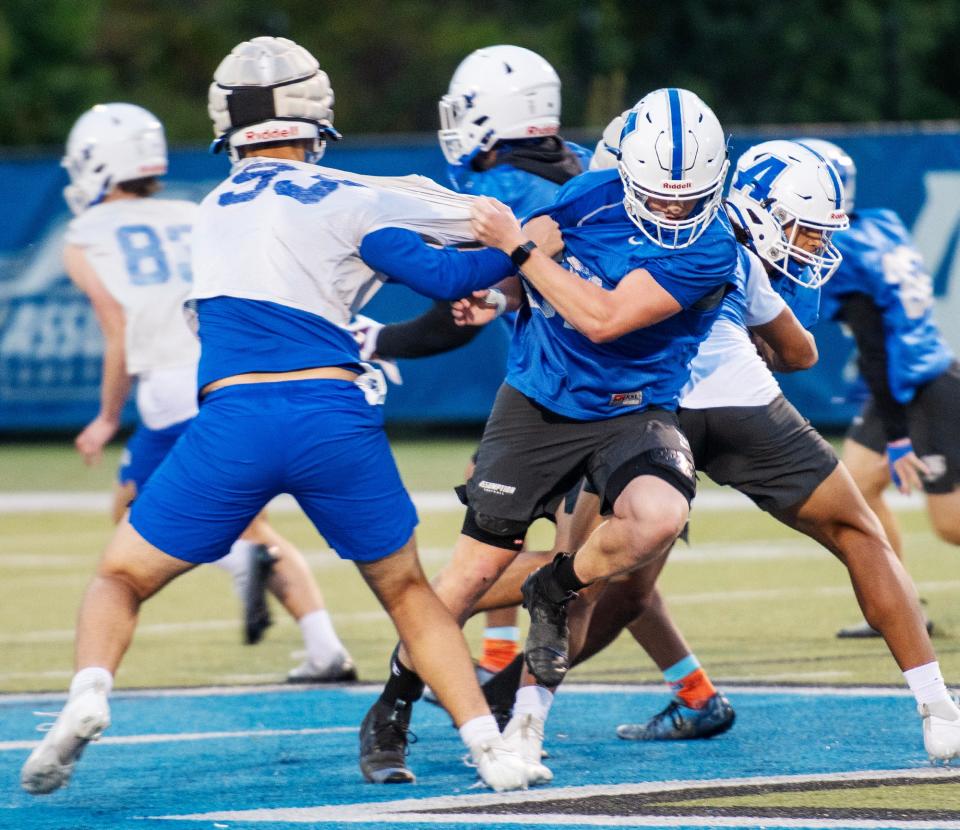 Assumption linebacker Owen Fitzgerald of Auburn, center, powers through during practice Thursday night.