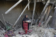 Afghan girl salvages belongings from her destroyed house after an earthquake in Gayan district in Paktika province, Afghanistan, Sunday, June 26, 2022. A powerful earthquake struck a rugged, mountainous region of eastern Afghanistan early Wednesday, flattening stone and mud-brick homes in the country's deadliest quake in two decades, the state-run news agency reported. (AP Photo/Ebrahim Nooroozi)