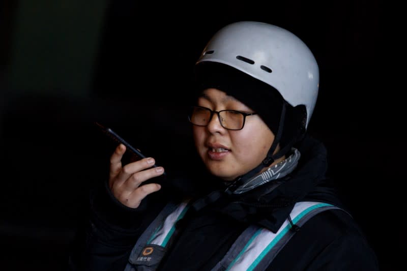 Substitute driver Liu Pengfei sends a voice message to a client that he has acquired through the ride-hailing service platform DiDi Chuxing outside a restaurant in Beijing