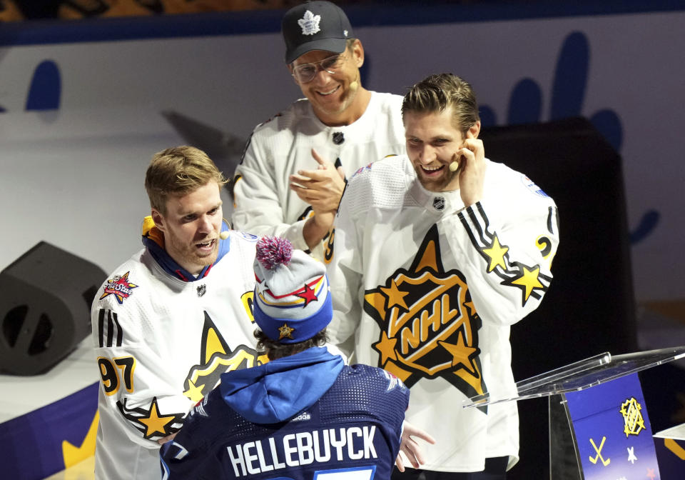 Connor McDavid ,left, of Team McDavid welcomes Connor Hellebuyck as the team's first pick as Leon Draisaitl, right, and Will Arnett look on during the NHL All-Star hockey week draft in Toronto on Thursday, Feb. 1, 2024. (Nathan Denette/The Canadian Press via AP)