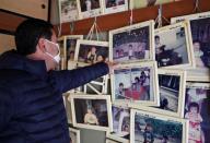 Kazuo Ouchi points to a family photograph hanging on a wall of their now-abandoned house in Iitate, Fukushima, Japan