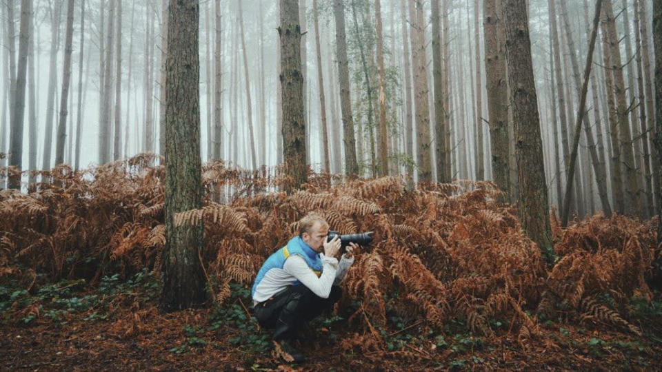 Photographer taking pictures with a camera in a misty woodland