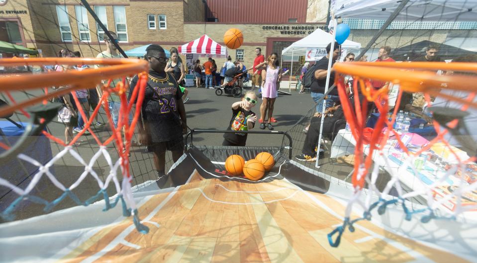 Maya Gless, 4, of Massillon shoots hoops at a booth at the Downtown Massillon Fun Fest.