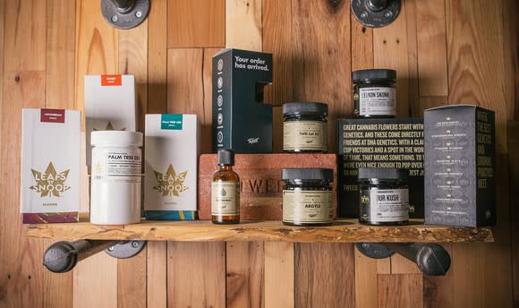 Tweed-branded products lined up in boxes and bottles on a wood mantle in front of a wood-paneled wall.