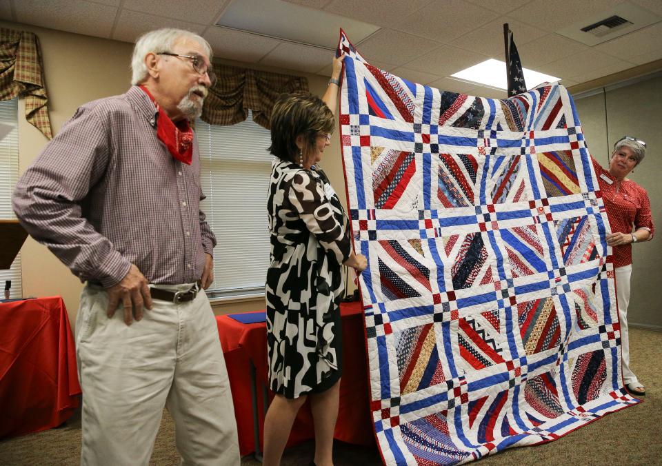 The Daughters of the American Revolution honored three veterans Friday, Nov. 10, 2023, at Northport Baptist Church. Veteran Robert O’Brien watches as DAR members Dawn Crocker and Kim Armstrong display a quilt given him by the Quilts of Valor organization.