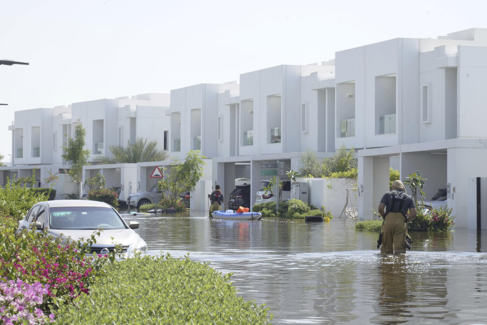 Civil defense officials bring water on a raft to a family in the Mudon neighborhood in Dubai, United Arab Emirates, Thursday, April 18, 2024. The United Arab Emirates attempted to dry out Thursday from the heaviest rain the desert nation has ever recorded — a deluge that flooded out Dubai International Airport and disrupted flights through the world's busiest airfield for international travel. (AP Photo/Jon Gambrell)