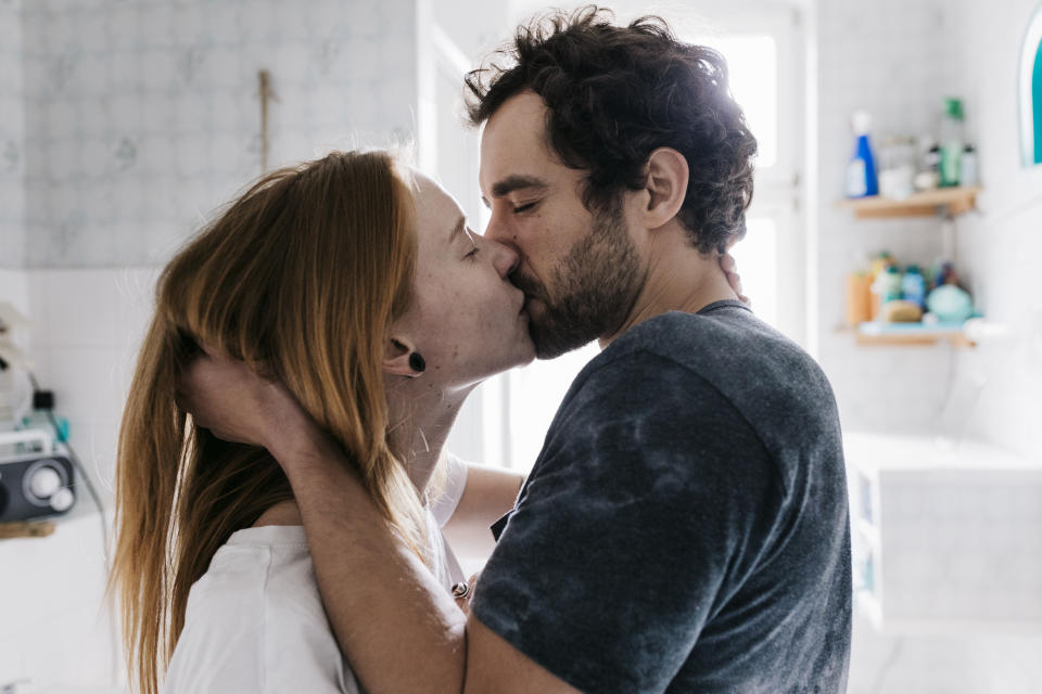 Couple kissing in bathroom. (Getty Images)