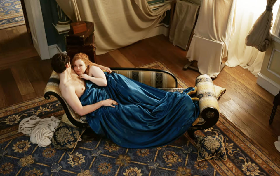 Nicola Coughlan and Luke Newton in "Bridgerton" lying on a chaise lounge during an intimate scene