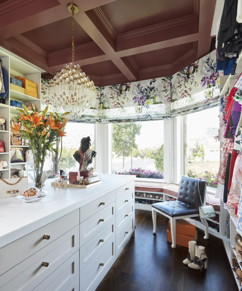 A walk-in closet with open rails, bay window, white storage island and beamed ceiling