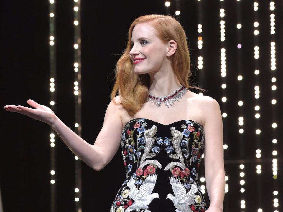 Jessica Chastain looks to the side with one hand extended