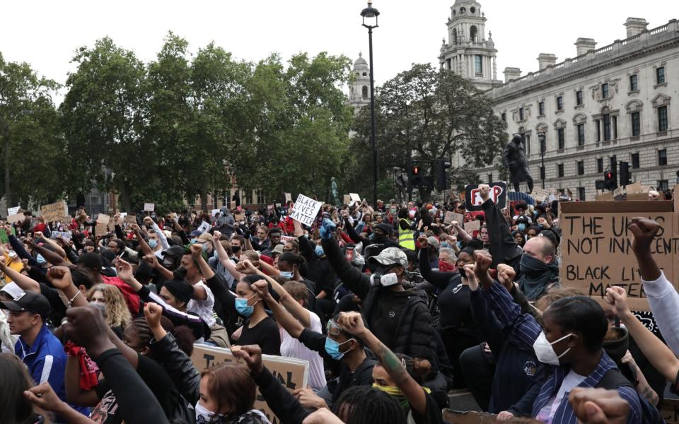 Protesters wearing face masks, hold up placards and raise clenched fists during a Black Lives Matter protest outside the Houses of Parliament on June 3, 2020 - Dan Kitwood/ Getty Images Europe