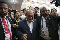 Papua New Guinea Prime Minister Peter O'Neill is escorted by security as he is chased by reporters after reading his statement at the end of the APEC 2018 summit at Port Moresby, Papua New Guinea on Sunday, Nov. 18, 2018. (AP Photo/Aaron Favila)