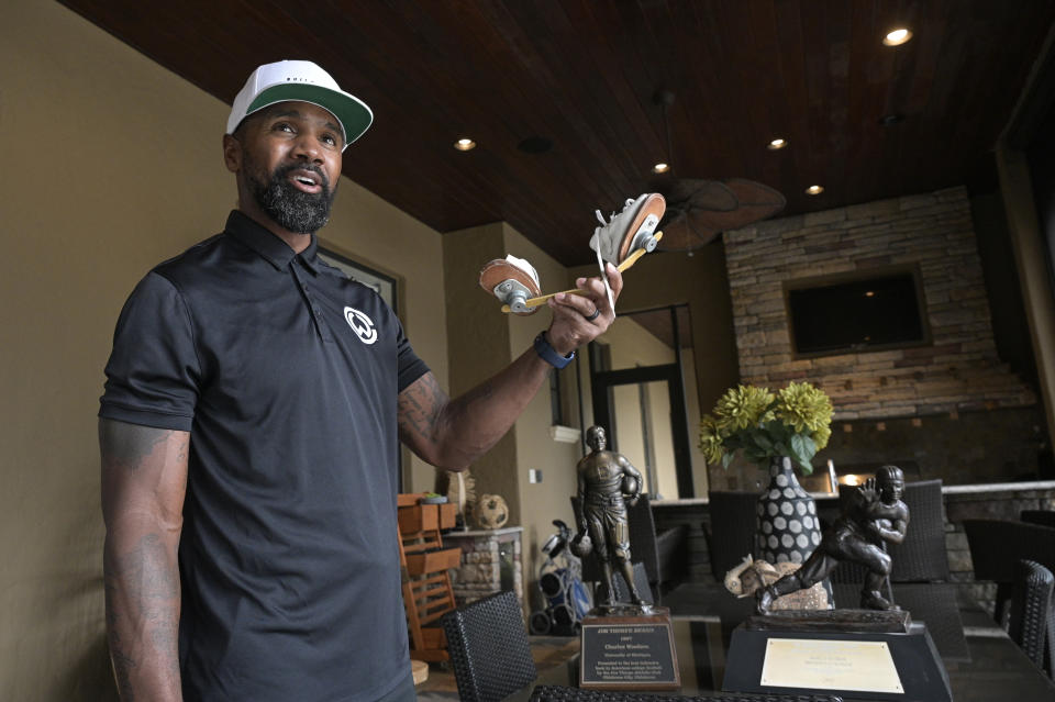 Former NFL football player Charles Woodson stands with his collegiate Jim Thorpe Award, Heisman Trophy and clubfoot brace shoes during an interview at his home Tuesday, June 15, 2021, in Orlando, Fla. Growing up in Fremont, Ohio, Woodson overcame the deformity and went on to become a first-ballot Pro Football Hall of Famer, who will be inducted about 100 miles from his hometown on Sunday, Aug. 8. (AP Photo/Phelan M. Ebenhack)