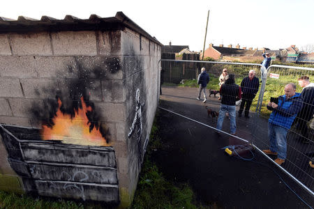 FILE PHOTO: People view new work by the artist Banksy that appeared during the week on the walls of a garage in Port Talbot, Britain December 22, 2018. REUTERS/Rebecca Naden/File Photo